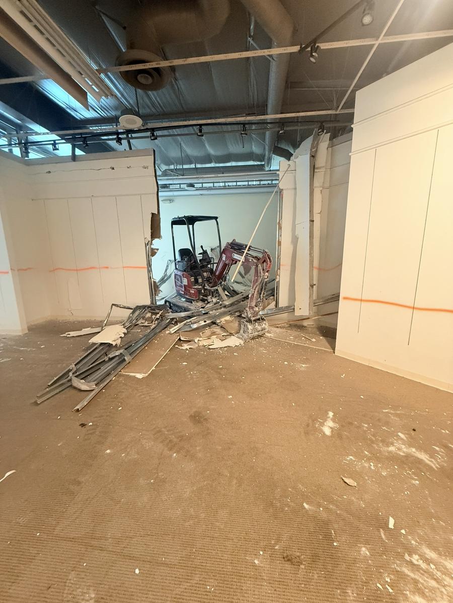 Mini excavator working through a wall in a retail space