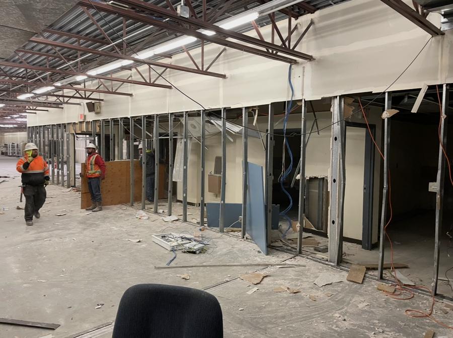 Metal-stud partition walls being demolished with workers on site