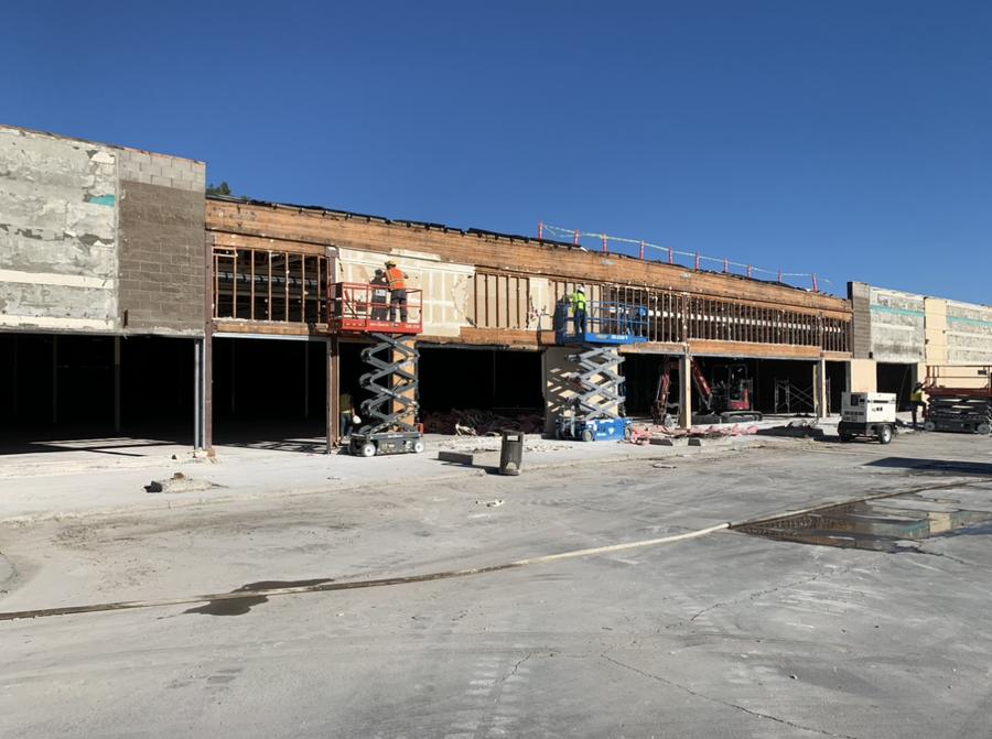 Workers on scissor lifts demolishing the facade of a retail building